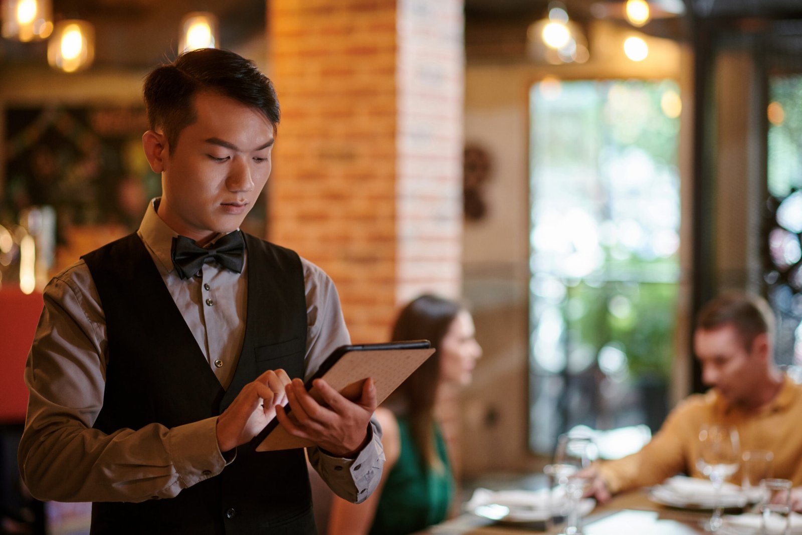 Restaurant waiter sending order to kitchen via application on tablet computer